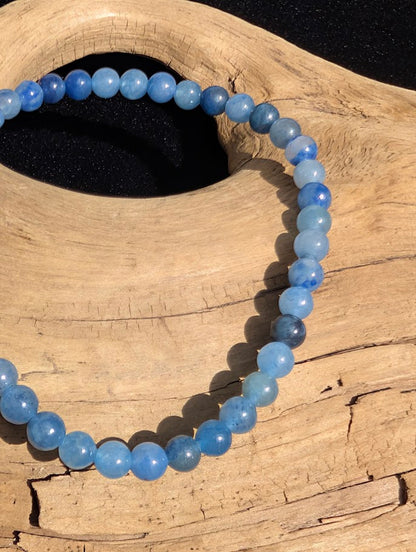 Macro close-up of 4mm translucent Blue Aventurine beads showing natural dumortierite inclusions and a blue stretch cord.