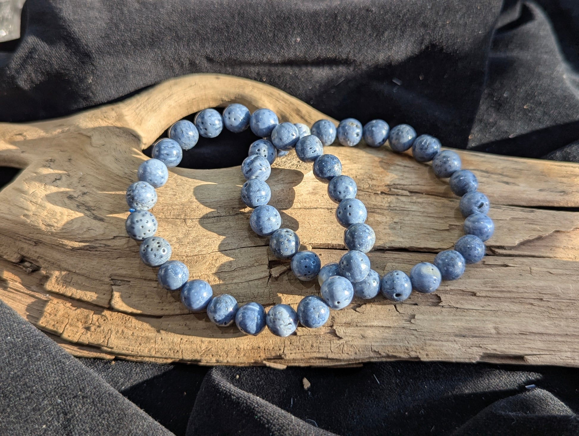 An 8mm Blue Sponge Coral round bead stretch bracelet positioned on a neutral presentation surface, demonstrating bead uniformity, precise lapidary polish, and a stabilized indigo-blue structural color profile.