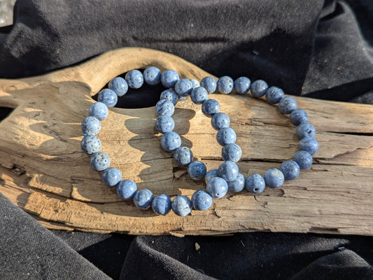 An 8mm Blue Sponge Coral round bead stretch bracelet positioned on a neutral presentation surface, demonstrating bead uniformity, precise lapidary polish, and a stabilized indigo-blue structural color profile.