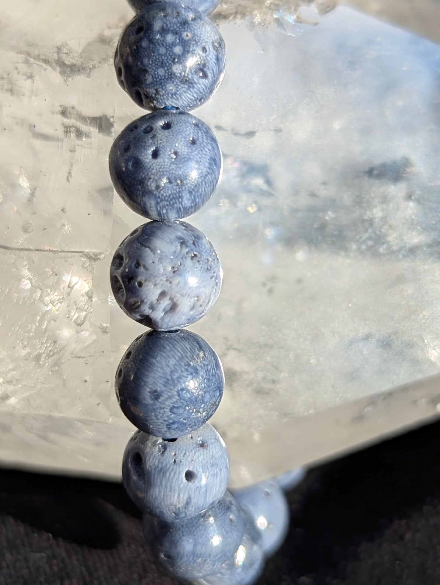Macro close-up view of polished 8mm Blue Sponge Coral spheres, highlighting the fine organic skeleton porosity and deep blue coloration of the calcium carbonate matrix.