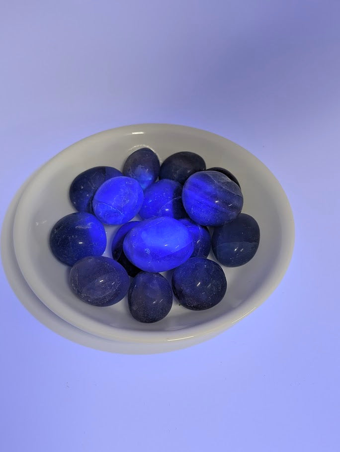 Blue Fluorite tumbled stones under UV light