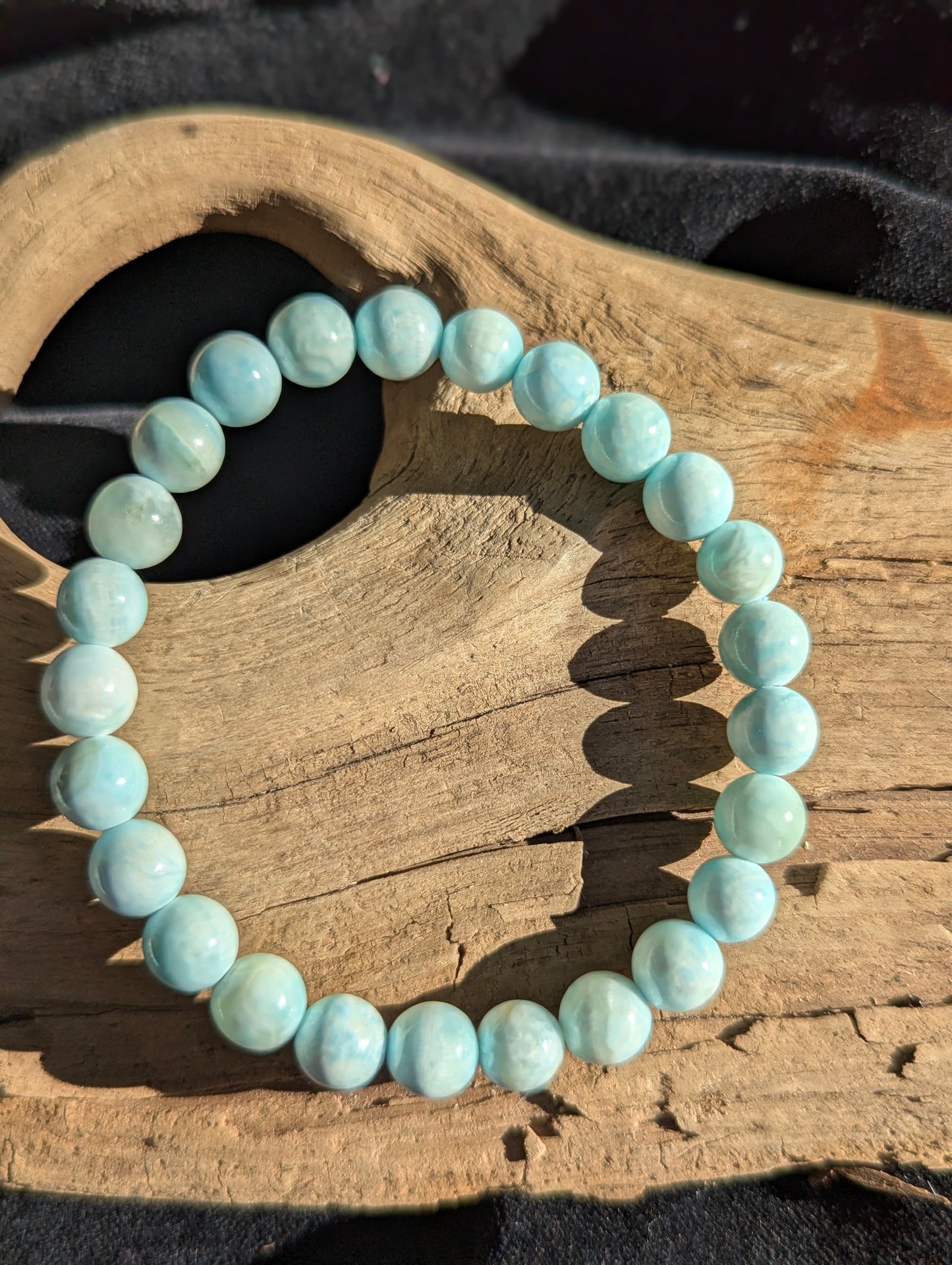 A close-up view of an 8mm Blue Hemimorphite beaded stretch bracelet with 25 beads held in hand, highlighting smooth surfaces and natural pitting.