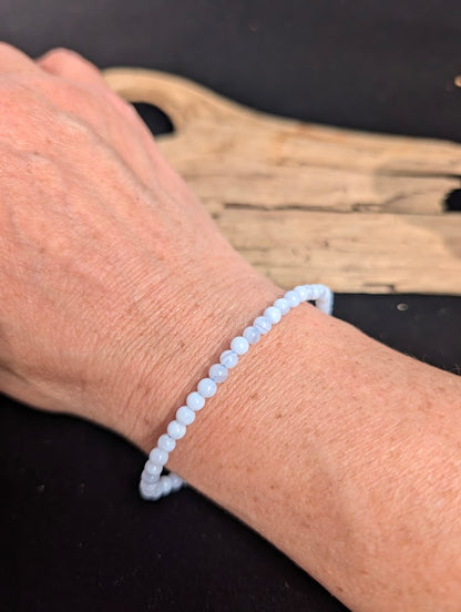 Natural sunlight on a delicate 4mm pale blue Blue Lace Agate stretch bracelet worn on a wrist.