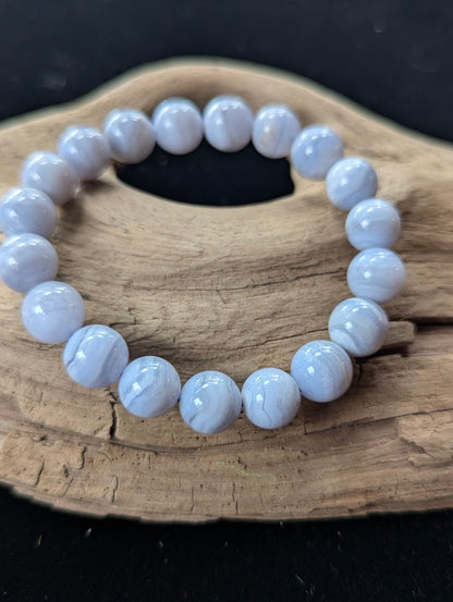 10mm natural Blue Lace Agate bead bracelet from Namibia displayed on driftwood