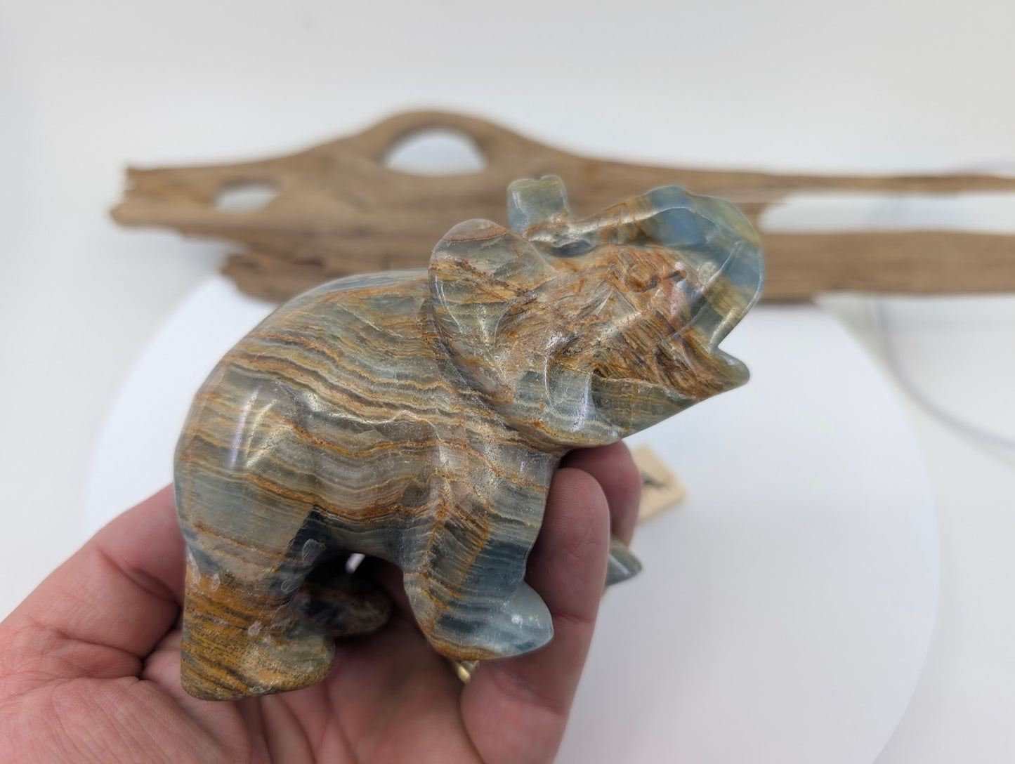 Hand-held view of Blue Onyx elephant specimen A1 providing scale and showing polished silk luster.