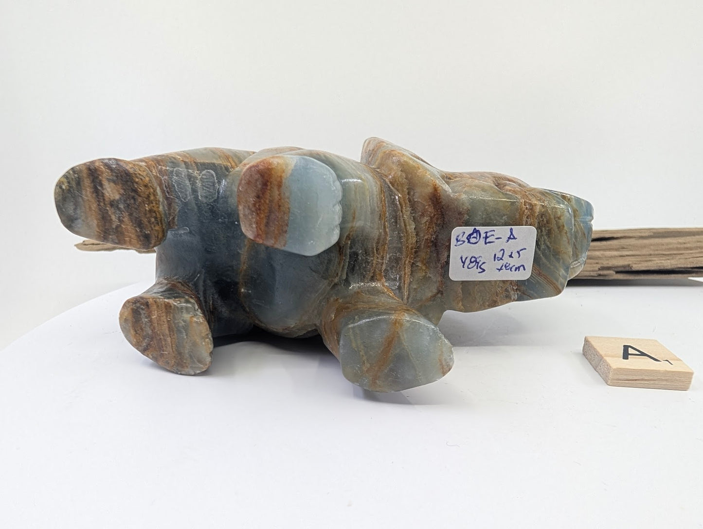 Underside of Blue Onyx elephant specimen A1 showing weight label 481g and raw calcite texture.