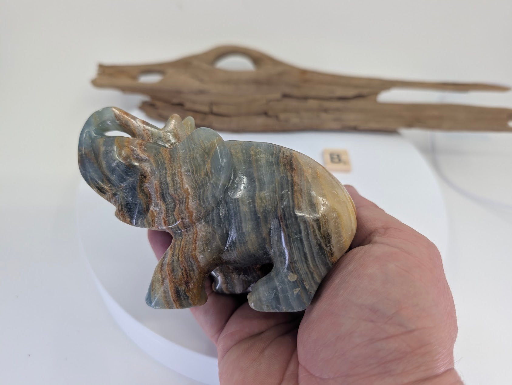 Hand-held view of Blue Onyx elephant specimen B3 providing scale and showing atmospheric blue-grey zones.
