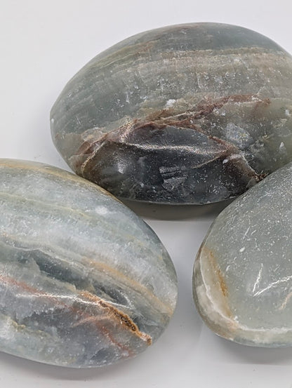 Close-up of Blue Onyx palm stones showing layered banding and subtle translucence