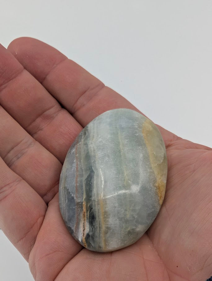 Blue Onyx palm stone in hand showing grey-blue banded color and fine polished surface