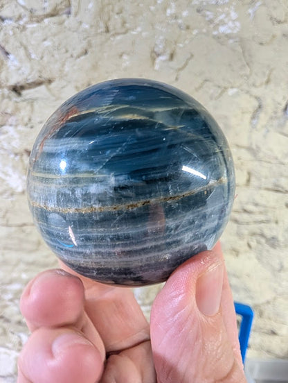 Angled view of blue onyx sphere revealing soft banding and shine