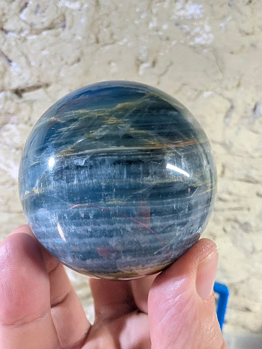 Side view of polished 63mm blue onyx sphere showing layered texture