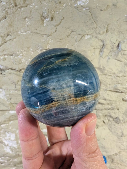Front view of 67mm blue onyx sphere showing golden seam and banded contrast