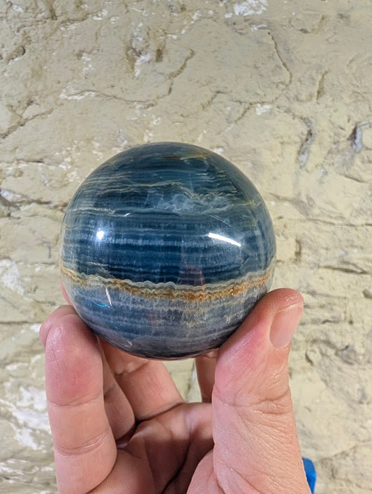 Side angle of blue calcite sphere with rich banding and polish