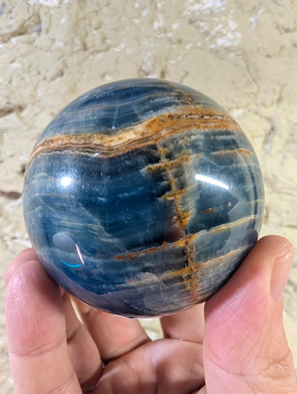 Front view of 72mm Argentinian blue onyx sphere with cross-banding