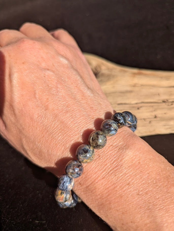 10mm AAA Grade Namibian Blue Pietersite beaded stretch bracelet worn on a wrist for scale.