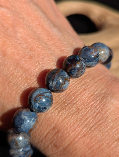 2mm AAA Grade Namibian Blue Pietersite beaded stretch bracelet worn on a wrist in natural sunlight.