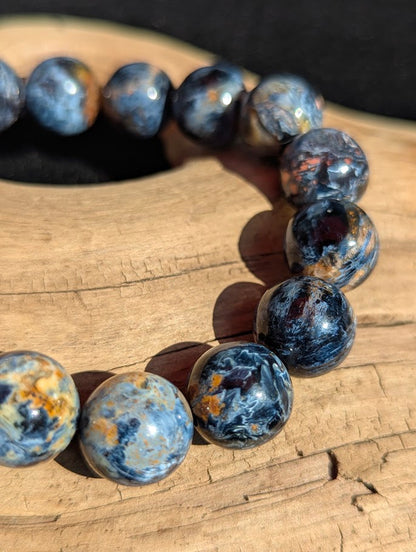 Macro photograph of 13mm Blue Pietersite quartz beads highlighting chaotic swirling chatoyancy and high vitreous lustre.