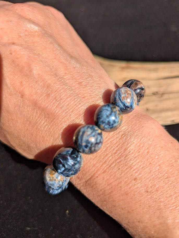 13mm AAA Grade Namibian Blue Pietersite beaded stretch bracelet worn on a wrist for scale demonstration.