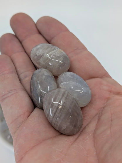 Blue Rose Quartz tumbles in hand for size reference