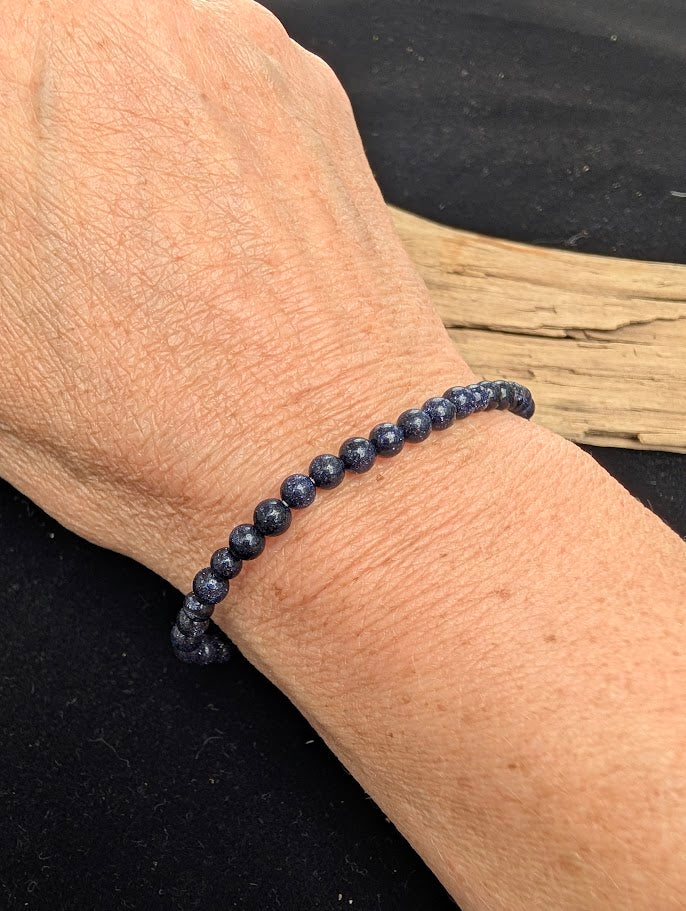 4mm polished Blue Sandstone beaded stretch bracelet worn on a wrist for delicate size scale.