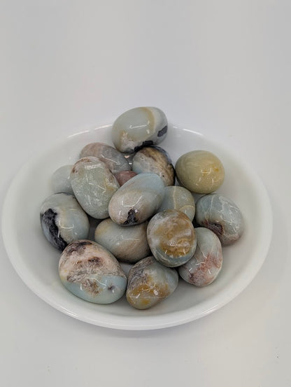 Blue Sky Opal tumbled stones in a white dish showing soft blue and cream tones