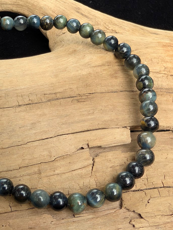 Macro close-up of 4mm polished Blue Tiger Eye beads highlighting the high-gloss finish and the silky, natural chatoyant flash.
