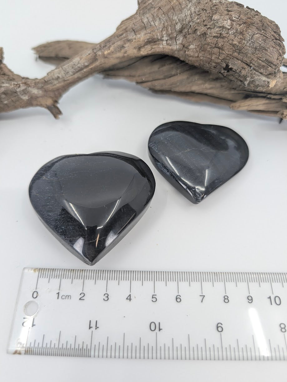 Angled view of polished Blue Tiger Eye hearts on white background.