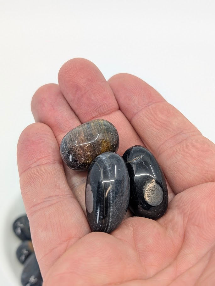 Blue Tiger Eye tumbled stones shown in hand for scale