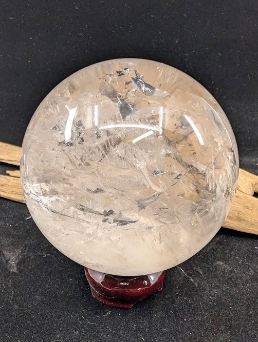 Front view of a 93mm Brazilian clear quartz enhydro sphere resting on a display stand, showcasing its pristine polish and internal inclusions.