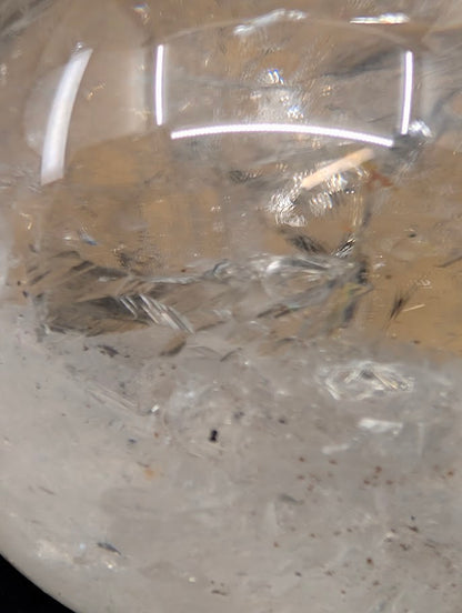 Detailed view of a 1.12 kg clear quartz enhydro sphere from Brazil on a display stand, emphasizing its optical clarity and internal fracture planes.