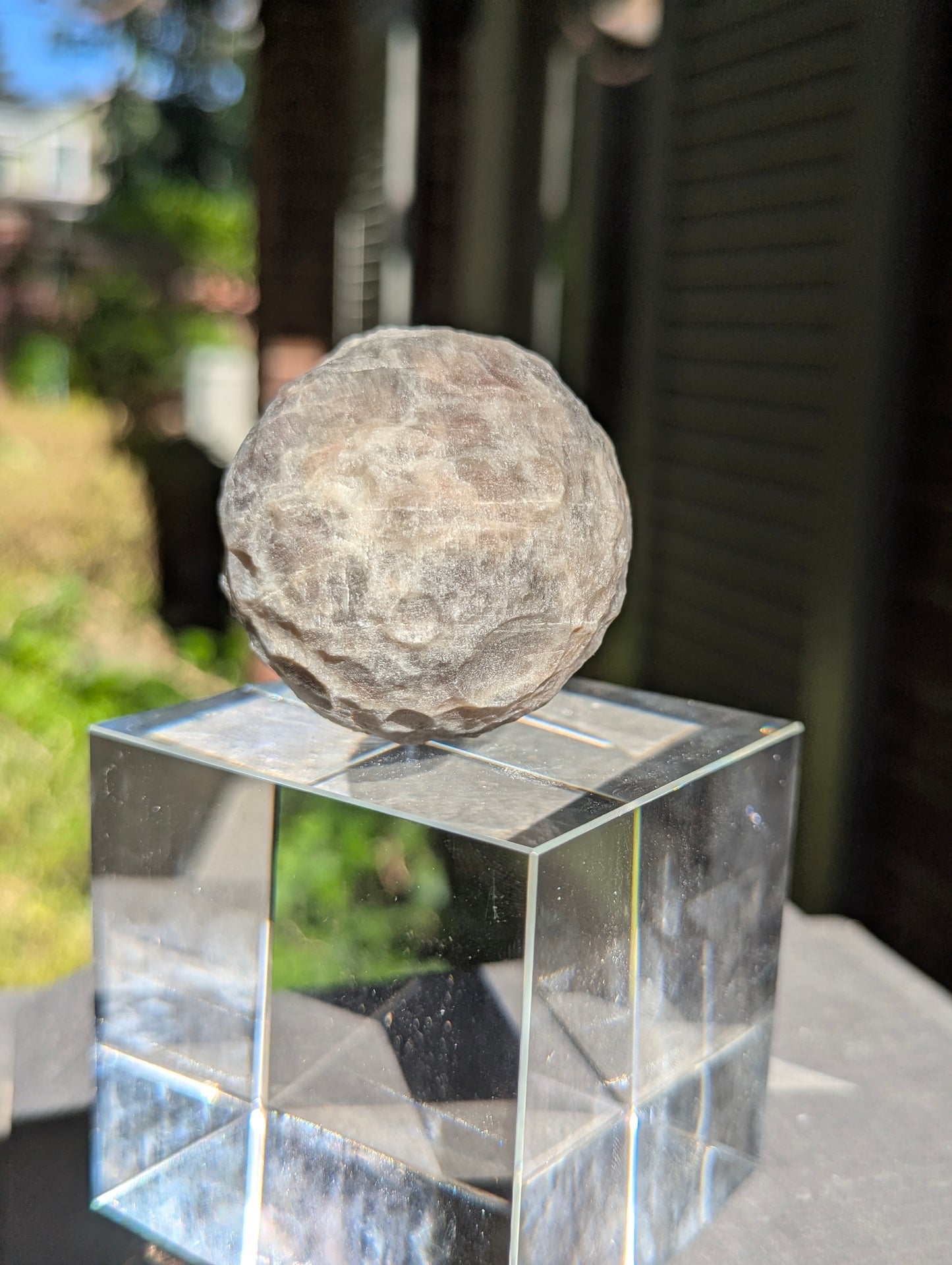 A 50 mm (1.97 in) Brown Moonstone carved moon sphere exhibiting a soft, sweeping adularescent glow.