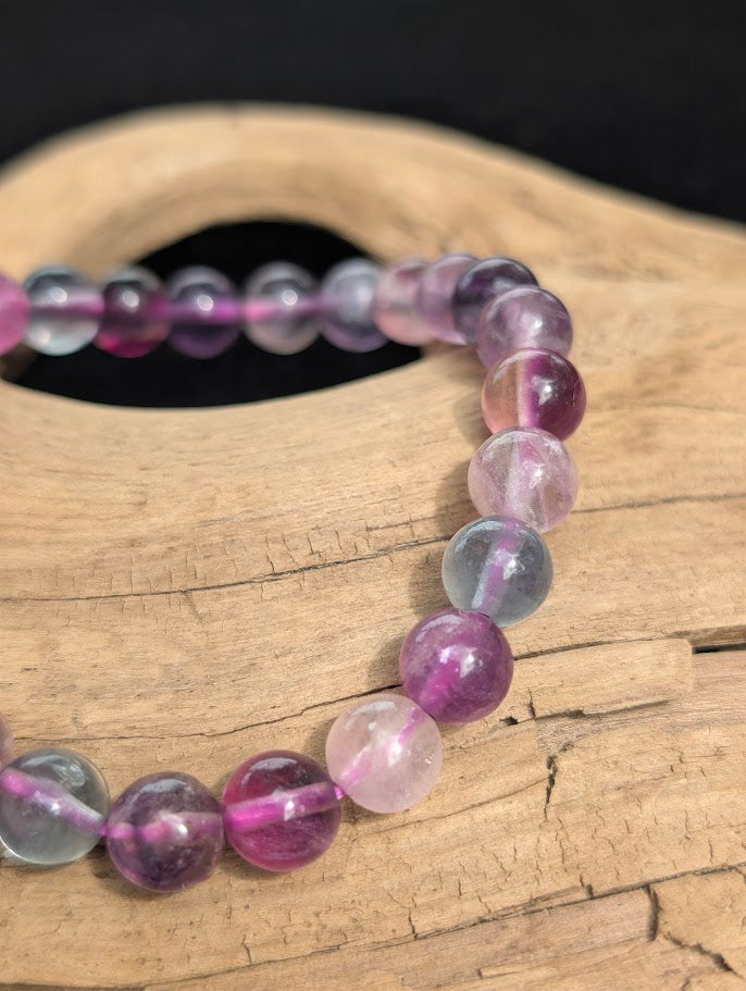 Macro close-up of 8mm translucent Candy Fluorite beads showing natural internal structures and a pink stretch cord.