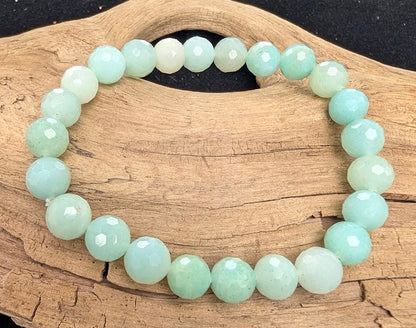 8mm faceted HQ Caribbean Calcite beaded stretch bracelet resting on a driftwood display, showing soft ocean blue and cloudy white tones.