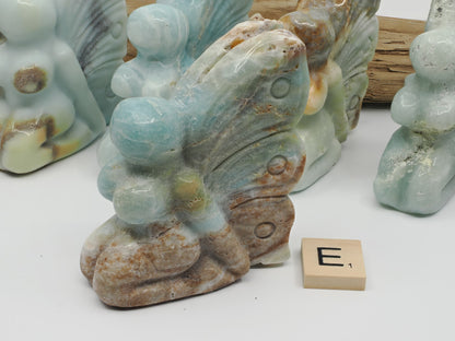 Caribbean Calcite butterfly fairy E with sandy tan aragonite base and blue wing tips.