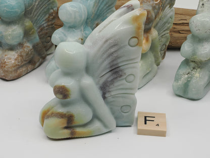 Polished Caribbean Calcite fairy F showing dark mineral beauty mark on a pale blue wing.