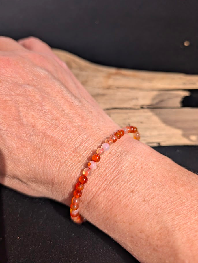 Natural sunlight on a 4mm orange Carnelian stretch bracelet worn on a wrist.