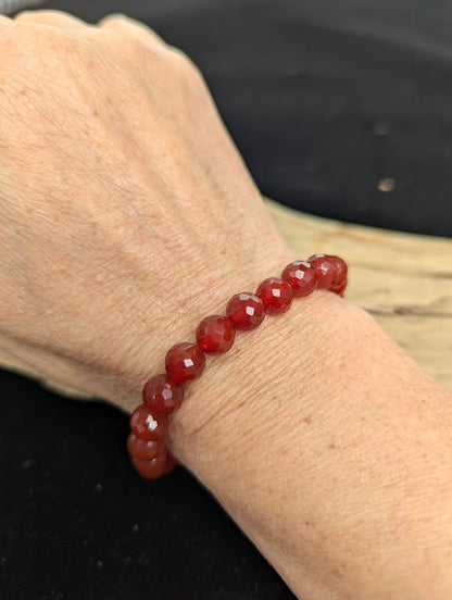 8mm faceted Carnelian beaded stretch bracelet worn on a wrist for size scale.