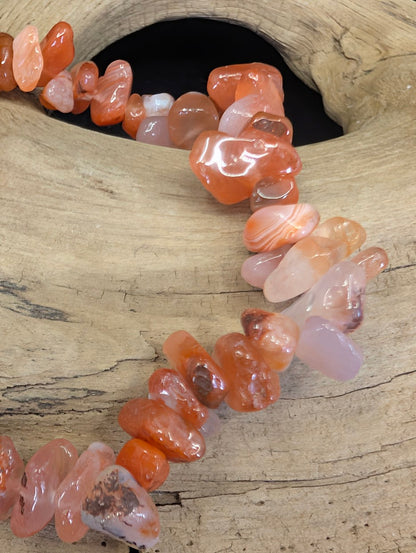 Close-up detail of polished Carnelian chips highlighting natural banding, translucency, and rich iron-oxide coloration.