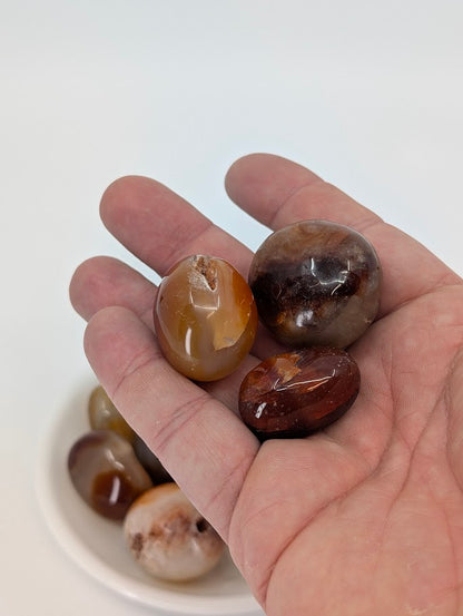 Hand holding polished Carnelian stones showing gloss and natural texture