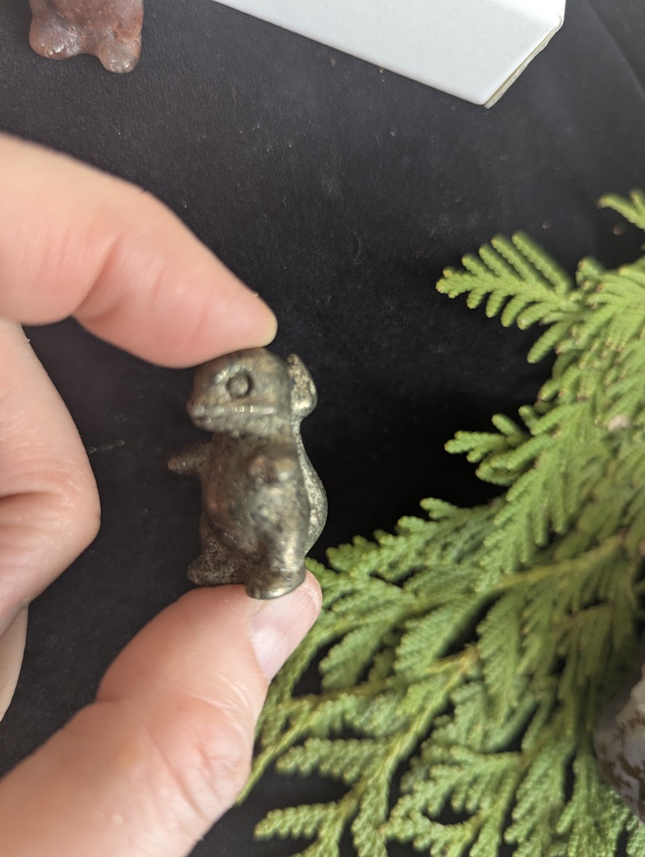 Side view of a 3cm Charmeleon carved from metallic Pyrite held in hand.