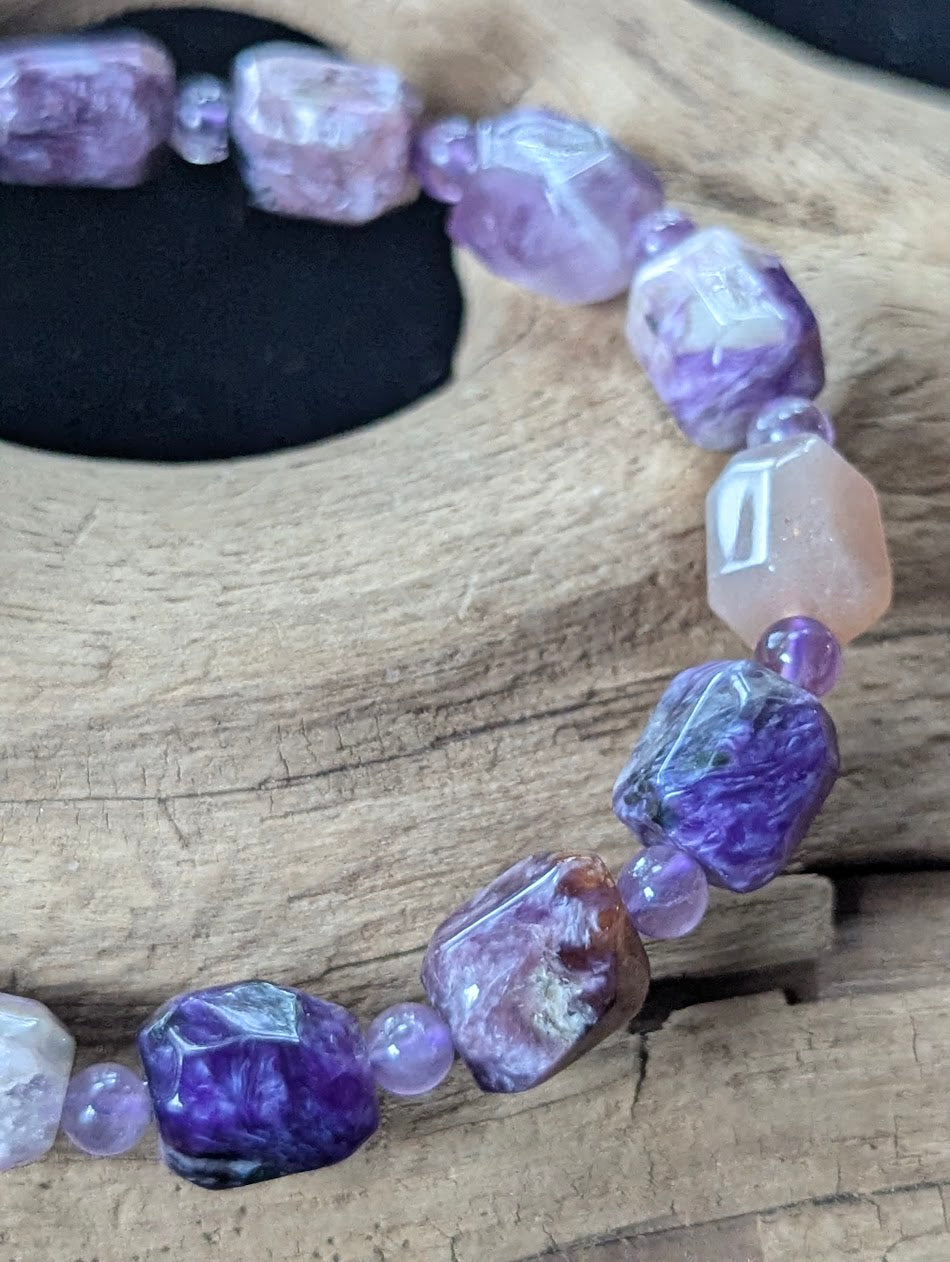 Close-up macro view of polished Charoite freeform nuggets showing swirling purple patterns alongside 4mm faceted Amethyst spacer beads.