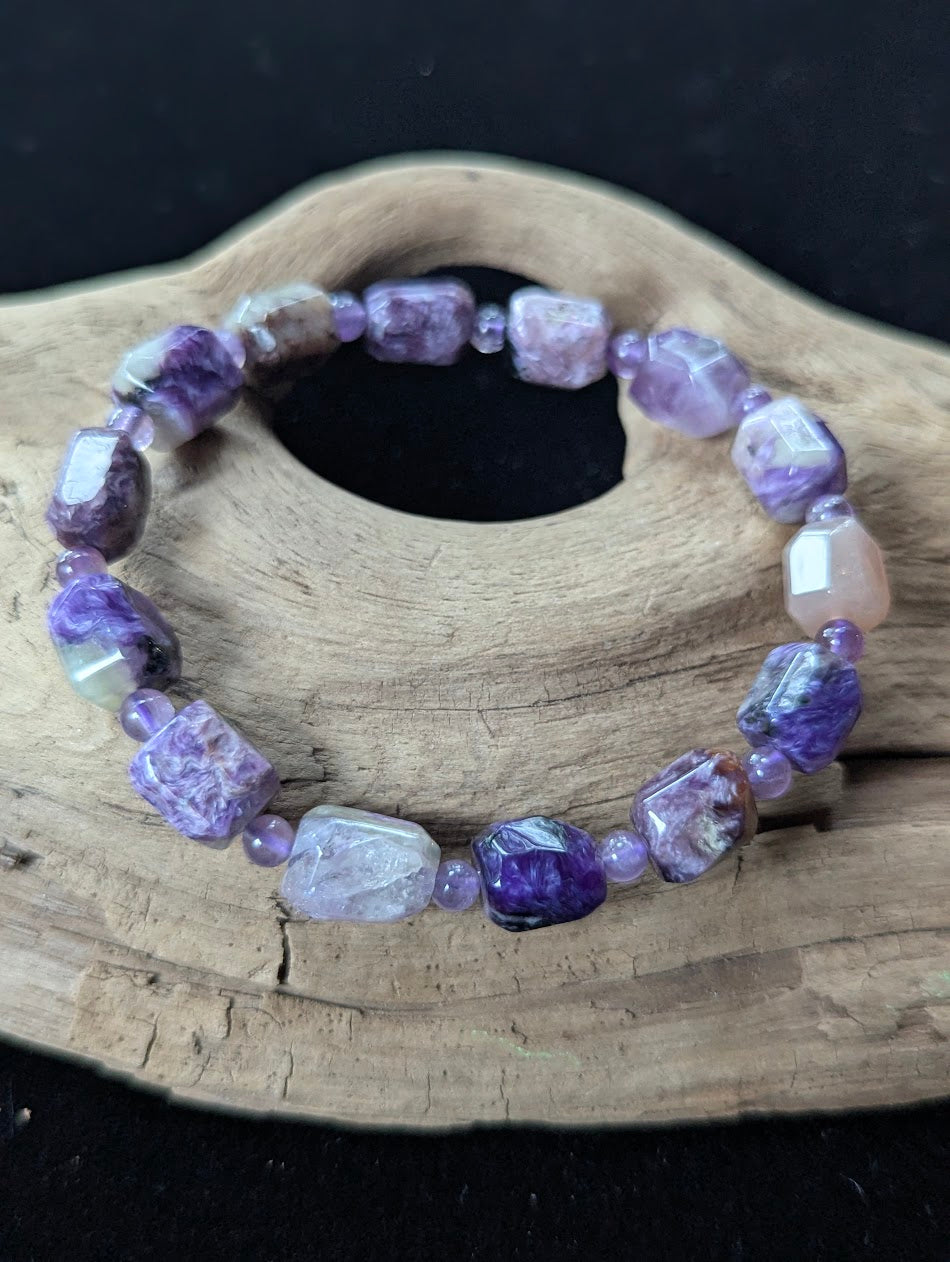 Rare Siberian Charoite freeform gemstone bracelet with faceted Amethyst accent beads resting on natural driftwood.