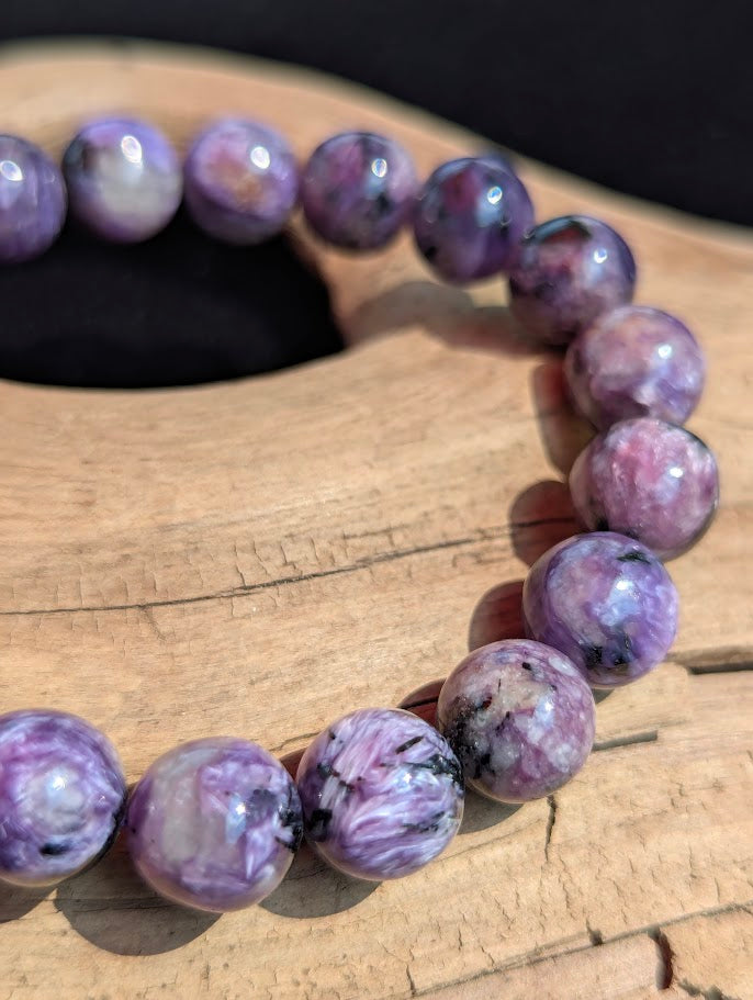 Macro detail of a 10mm AAA Charoite beaded bracelet displaying vibrant violet colouration and distinct fibrous crystal structure.
