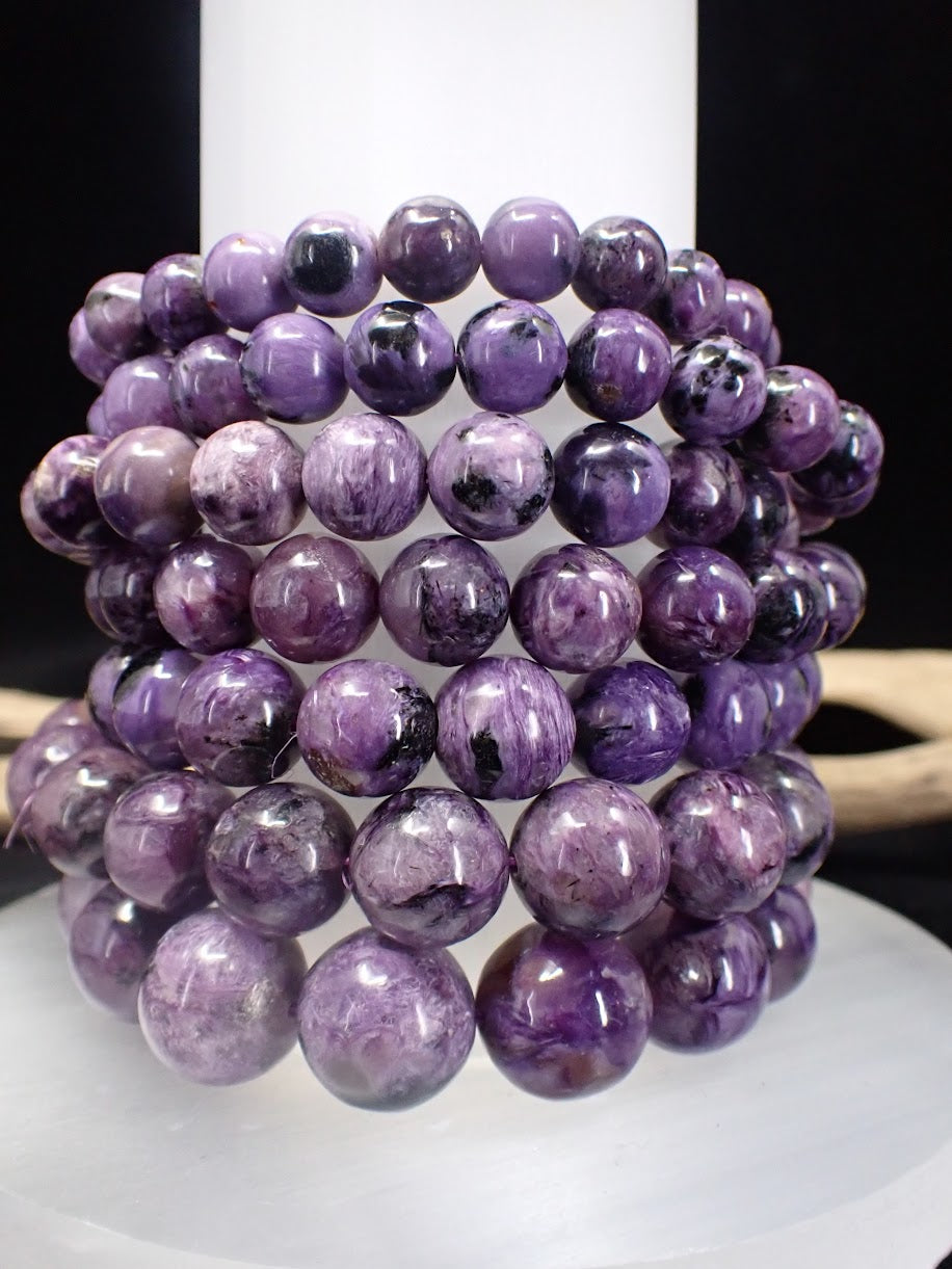 Stack of premium Charoite bracelets showing deep purple color and silky luster.