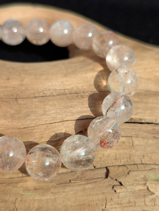 Macro detail of 11mm Cherry Blossom Garden Quartz beads capturing the faint hematite inclusions suspended in a highly transparent matrix.