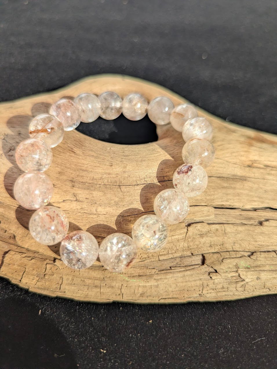 Intuitively selected 12mm AAA Grade Brazilian Cherry Blossom Garden Quartz beaded stretch bracelet displayed on driftwood.