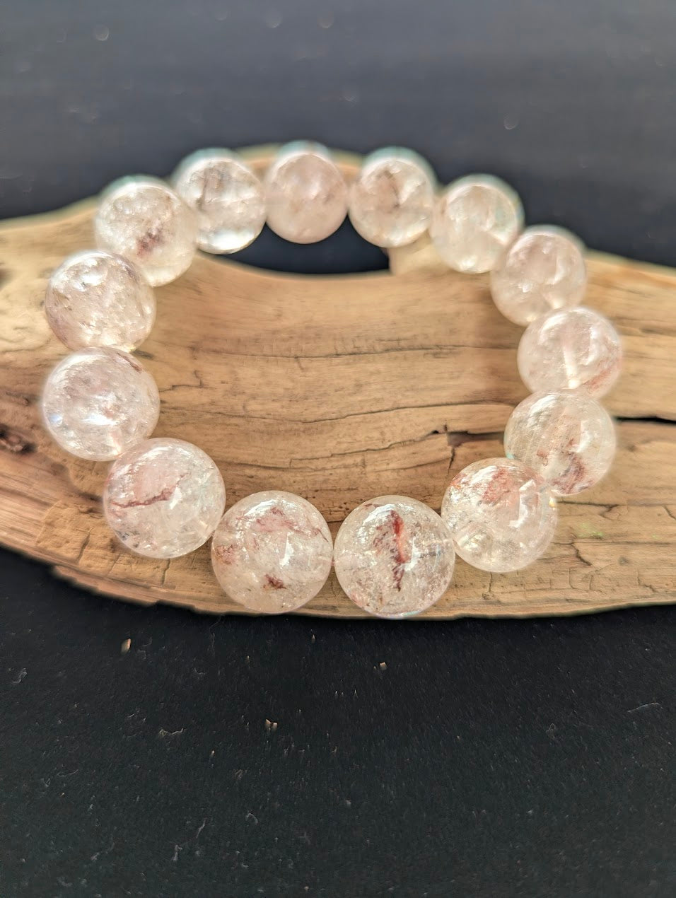 Intuitively selected 16mm statement AAA Grade Brazilian Cherry Blossom Garden Quartz beaded stretch bracelet resting on driftwood.