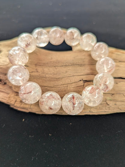 Intuitively selected 16mm statement AAA Grade Brazilian Cherry Blossom Garden Quartz beaded stretch bracelet resting on driftwood.