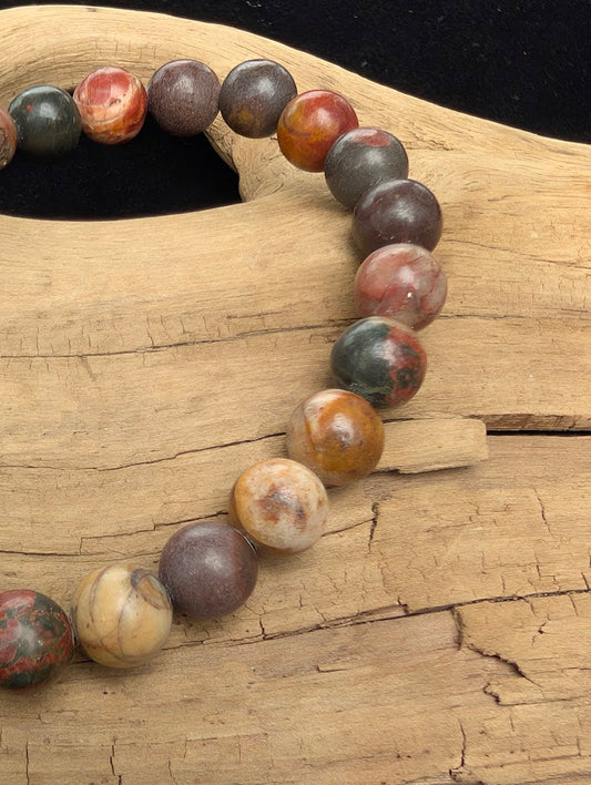 Macro close-up of 8mm polished Cherry Creek Jasper beads highlighting the high-gloss finish and natural red, green, and yellow brecciated patterns.