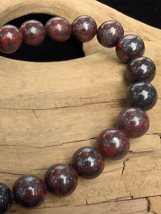 Macro close-up of 8mm polished Chicken Blood Jasper beads highlighting the high-gloss finish and natural red hematite inclusions.